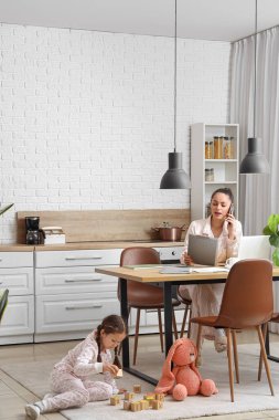 Annesi mutfakta çalışırken küçük kız küplerle oynuyor.