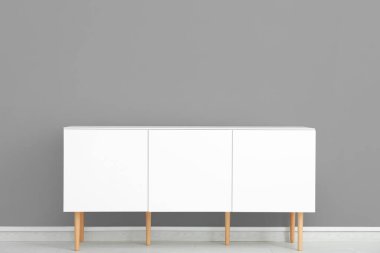 Gri duvarın yanındaki beyaz çekmeceler.