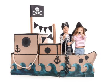 Beyaz arka planda karton gemide oynayan sevimli küçük korsanlar.