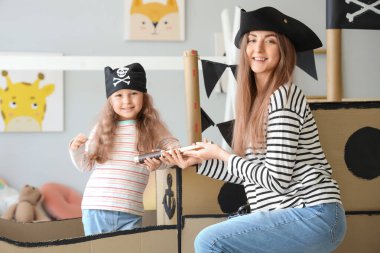 Annesiyle birlikte evde oynayan korsanlar gibi giyinmiş sevimli küçük bir kız.