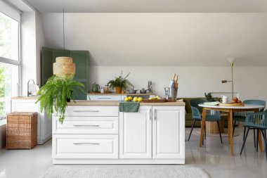 Beyaz tezgahlı ve yemek masalı modern mutfağın içi.