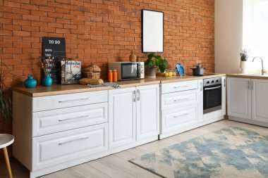 Modern mutfakta mikrodalga fırın, çatal bıçak ve elektrikli soba olan ahşap tezgahlar.