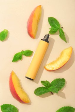 Şeftalili elektronik sigara ve bej arkaplanda nane.