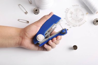 Beyaz arka planda farklı malzemeler ve elle dikiş makinesi olan bir kadın.