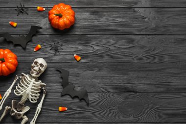 İskeletli kompozisyon, lezzetli mısır şekeri ve koyu ahşap arka planda Cadılar Bayramı dekoru.