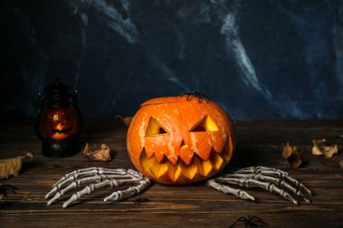 Ahşap masaya oyulmuş Cadılar Bayramı balkabağı ve iskelet eller