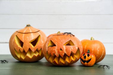 Ahşap masaya oyulmuş Cadılar Bayramı balkabakları ve örümcekler, yakın plan.
