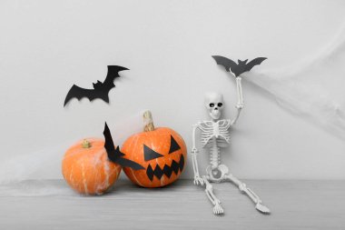 Cadılar Bayramı kutlaması için balkabakları, İskelet ve kağıt yarasalar gri ahşap masada