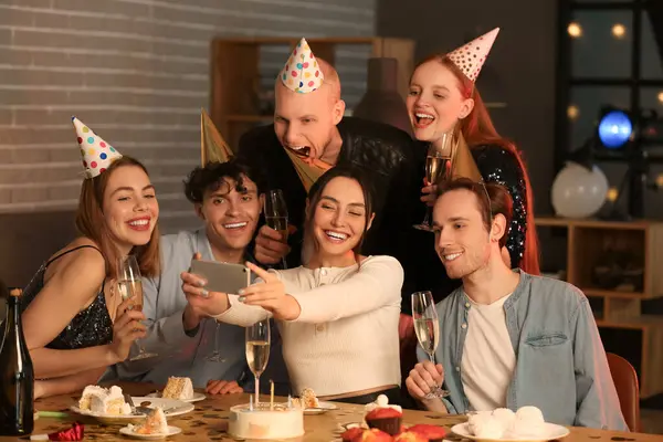 Group of young friends with mobile phone celebrating Birthday at night