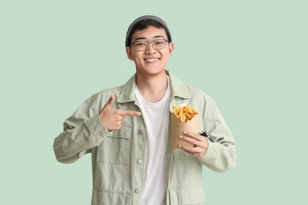 Jovem Asiático Apontando Para Batatas Fritas Fundo Verde — Fotografia de Stock