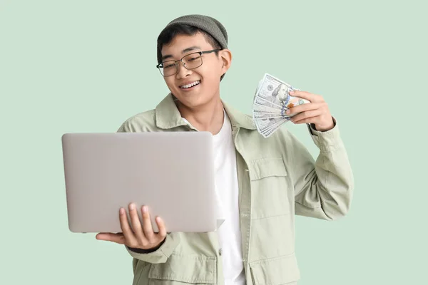Junger Asiate Mit Dollarnoten Und Laptop Auf Grünem Hintergrund — Stockfoto