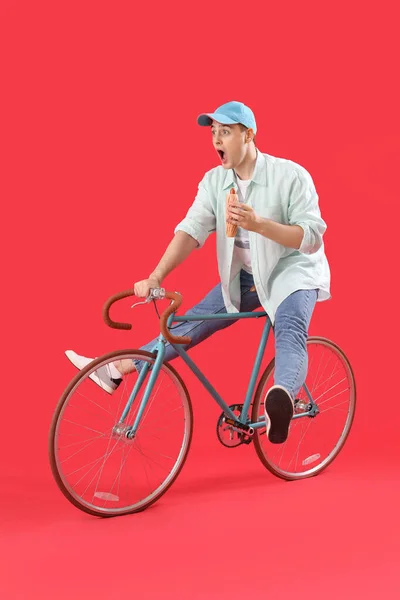 Sorpreso Giovane Uomo Con Gustoso Hot Dog Bicicletta Sfondo Rosso — Foto Stock