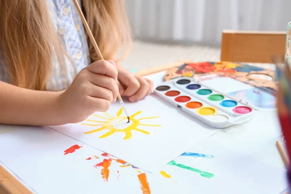 Cute little girl drawing with paints at home, closeup