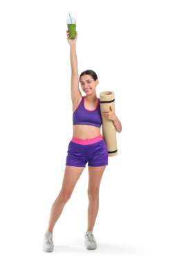 Beyaz arka planda sağlıklı smoothie ve fitness paspası olan sportif genç bir kadın.