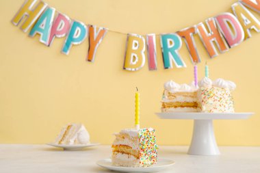 Parti çelengi ve nefis doğum günü pastasıyla bej duvarın yanındaki masada dur.