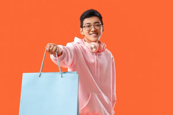 赤い背景のショッピングバッグを持つ若いアジアの男 — ストック写真