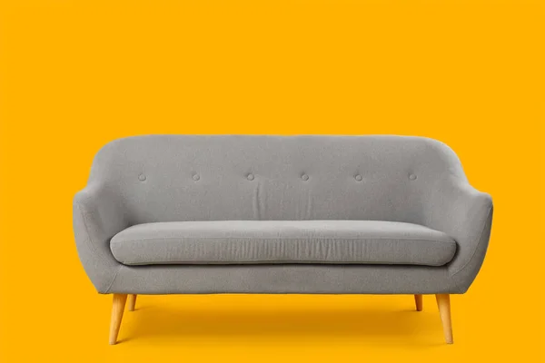黄色背景的舒适的灰色沙发 — 图库照片