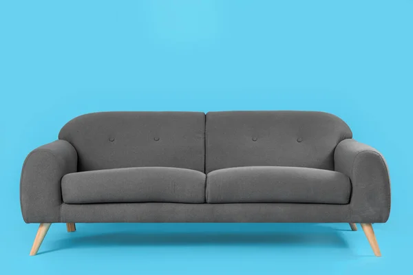蓝色背景的舒适的黑色沙发 — 图库照片