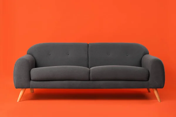红色背景的舒适的黑色沙发 — 图库照片