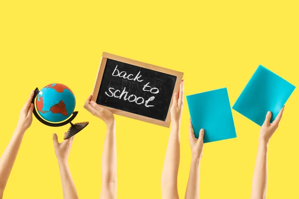世界を保持する女性の手 ノートブックとブラックボード 黄色の背景にSchoolに戻る — ストック写真