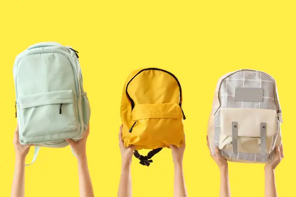 Sarı Arka Planda Farklı Sırt Çantaları Olan Kadın Elleri — Stok fotoğraf