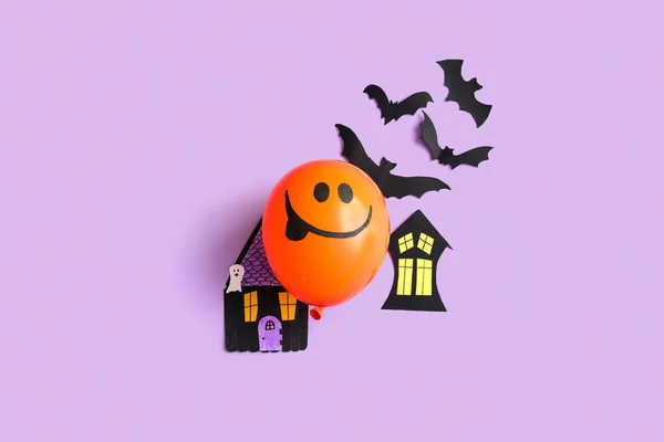 Funny Halloween balloon with party decorations on lilac background