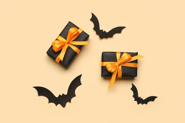 Paper bats for Halloween party and gift boxes on orange background
