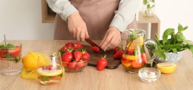 Mutfakta limonata için çilek kesen bir kadın.