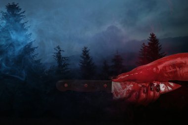 Hand with bloodstained knife in dark forest clipart