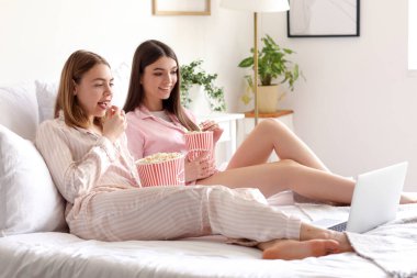 Patlamış mısırlı kadın arkadaşlar yatak odasında film izliyor.