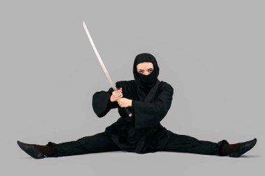 Gri arka planda kılıcı olan bir kadın ninja.