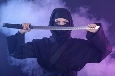 Karanlık arka planda kılıç taşıyan bir kadın ninja.