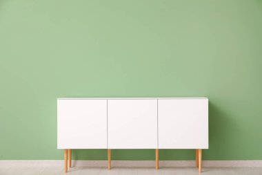 Yeşil duvarın yanındaki beyaz çekmeceler çok şık.