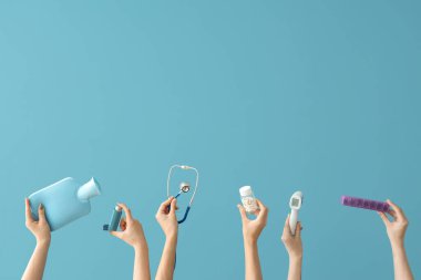 Mavi arka planda tıbbi aletleri ve hapları olan kadın eller.