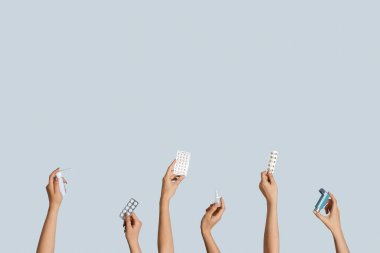 Kadın eli hap, astım spreyi ve gri arka planda spreyler.