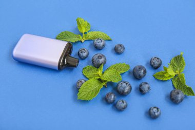 Mavi arka planda yabanmersini ve nane aromalı elektronik sigara.