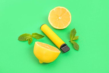 Yeşil arka planda limonlu ve naneli elektronik sigara.
