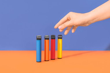 Renkli arka planda elektronik sigaralı bir kadın.