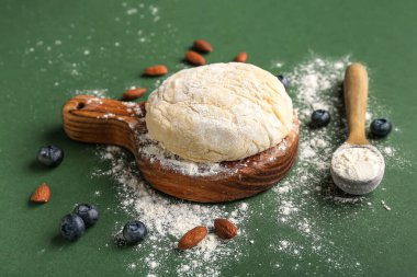 Yeşil zemin üzerine fırın hazırlamak için ham hamur, badem ve yaban mersinli kompozisyon