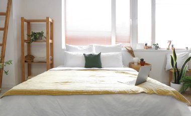 Yastıklı ve laptoplu büyük yatak şık bir odada.