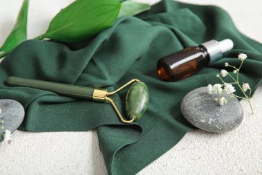 Serumlu taş yüz masajı silindiri ve hafif arka planda spa taşları.