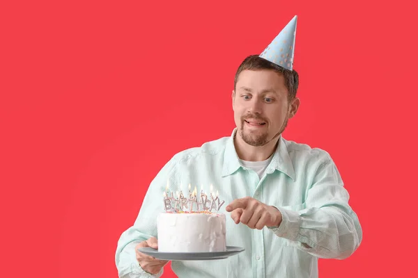 Man with birthday cake on red background