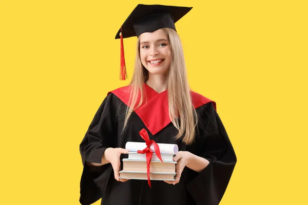 イエローバックグラウンドの卒業証書と本を持つ女性の大学院生 — ストック写真