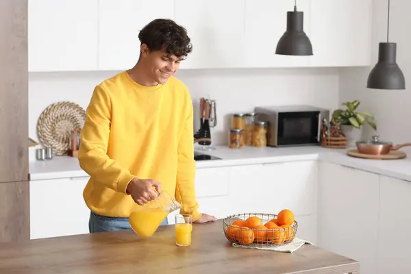 Genç Adam Mutfakta Portakal Suyunu Bardağa Dolduruyor — Stok fotoğraf