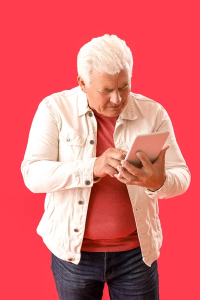 老年人在红色背景下使用平板电脑 — 图库照片