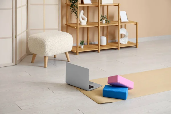 Interior of living room with yoga blocks, mat and laptop