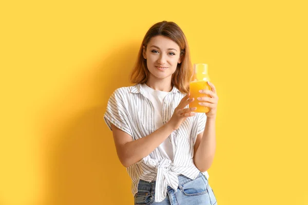 黄色い背景にジュースのガラス瓶が付いている若い女性 — ストック写真