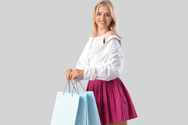 灰色の背景に買い物袋を持つ美しい若い女性 — ストック写真