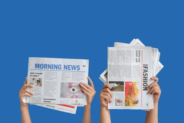青い背景に異なる新聞を持つ女性の手 — ストック写真