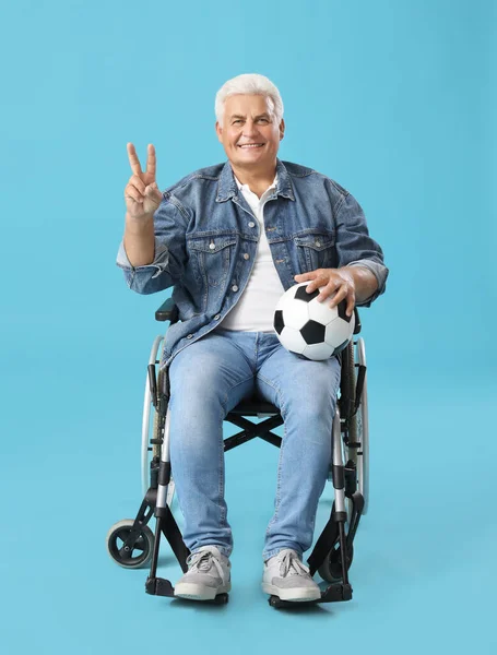 Reifer Mann Rollstuhl Mit Fußball Zeigt Siegesgeste Auf Blauem Hintergrund — Stockfoto